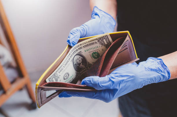 Image of Hand in a blue latex glove holding Black Leather Wallet With One Dollar Bill. Economy failure during Coronavirus COVID-19 outbreak.