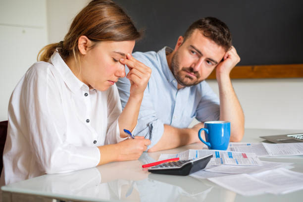 Stressed wife and husband with many debts calculating family income.Main focus on the woman
